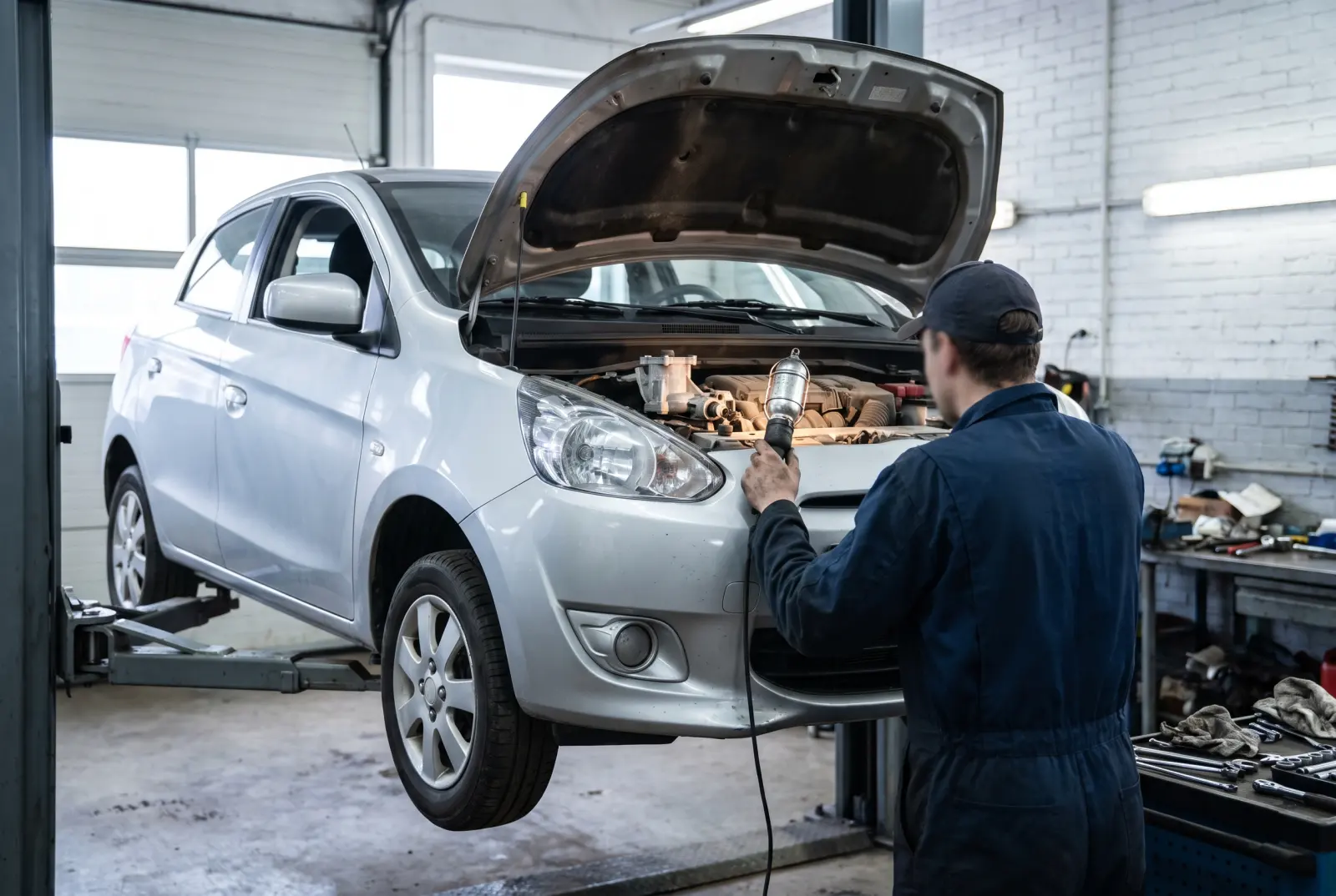 AI illustration: a generic silver 2015 subcompact hatchback sits raised on a two-post lift in a brightly lit, clean independent workshop